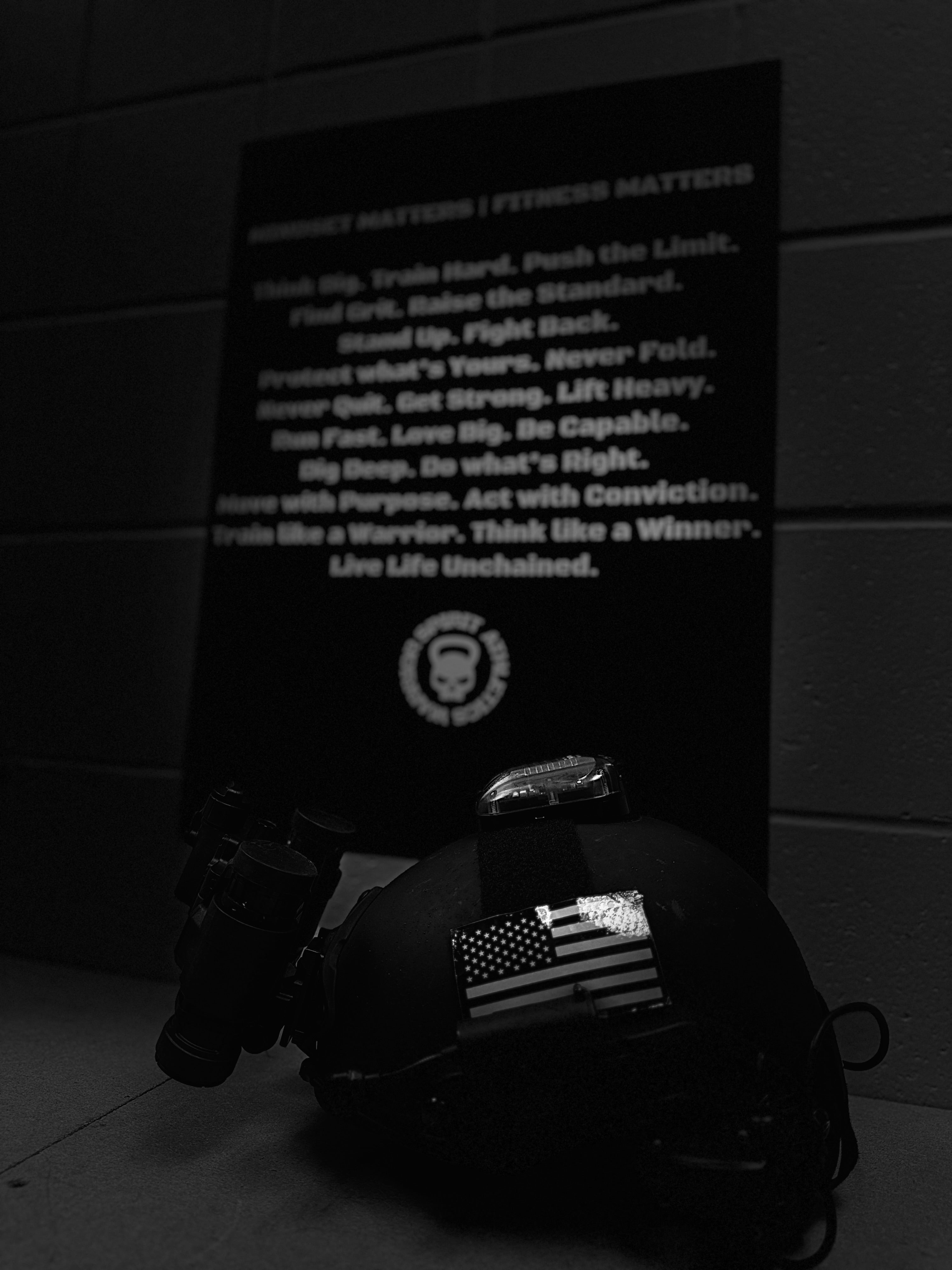 Black helmet with American flag patch on a dark background with motivational text
